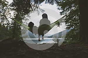 Small kid with mother on hammock on forest lake background