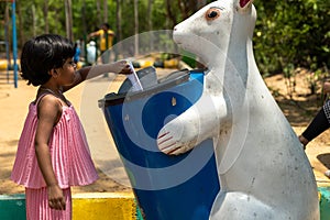 A small Kid putting waste paper in the dustbin