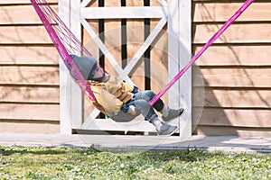 Small kid relaxing on pink hammock in spring garden