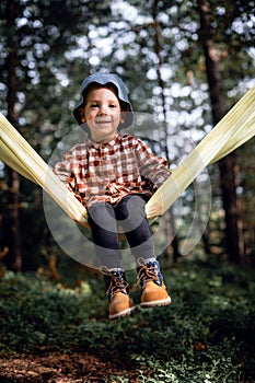 Small kid in yellow hammock in autumn forest