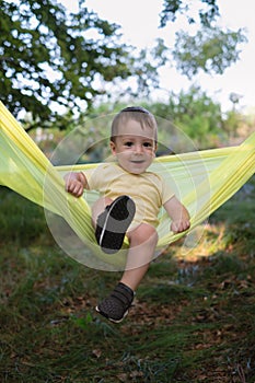 Small kid on yellow hammock in spring forest