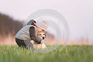 Small kid in yellow jacket with jack russel terrier puppy