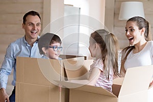 Small kids jump out cardboard boxes playing with parents