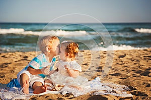 Small kids are kissing and having fun at beach together near the ocean, happy lifestyle family concept