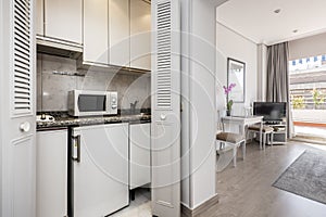 Small kitchen of an apartment with a small fridge under the gray granite