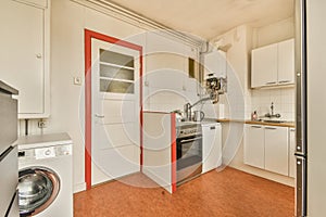 a white kitchen with a washing machine and a door photo