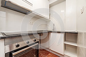 Small kitchen with recently installed white cabinets with gray worktops and stainless steel appliances and red stoneware floors photo