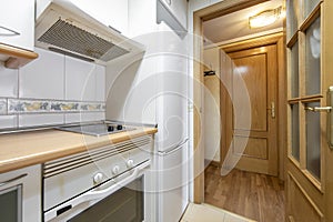 Small kitchen with white appliances and oak access door with beveled glass