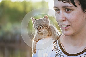 Small kitten sitting on the shoulder of a girl on a walk