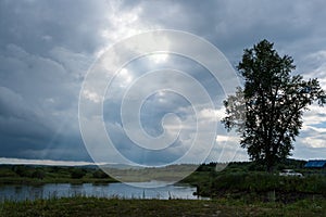 Small lake, fishermens and cloudy sky with sun rays.