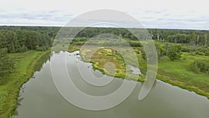 Small lake in the forest in summer. Stock footage. Aerial view of swampy terrain, meadow and grove.