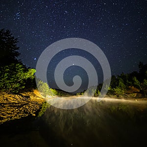 Small lake under stars at night with foggy vapour at summer