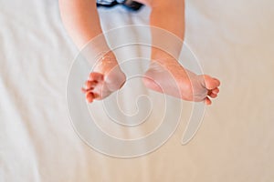 Small legs and feet of newborn baby on his bed