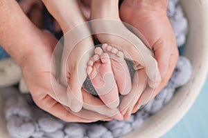 Small legs of a newborn child in the hands of his parents, tenderness and love in the hands