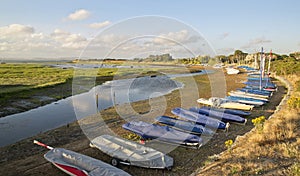 Small leisure boats moored at low tide in marina at Summer sunset