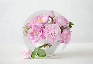 Small light pink bouquet of Roses in porcelain vase against of pale grey background.  Shallow depth of field. Selective focus