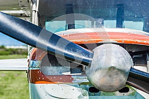 Small light utility aircraft, worn red and white paint, front view with propeller on sunny day.