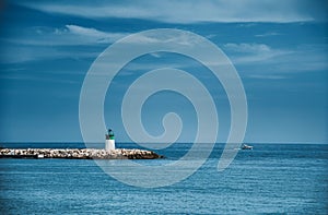 Small lighthouse on the pier of the calm blue sea