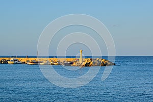 Small lighthouse, yachts on the pier, sunset at sea