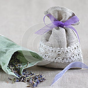 Small linen sack filled with dried lavender decorated with lacework and violet ribbon coqueand and one sachet is opened. Top view photo