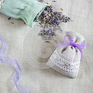 Small linen sack filled with dried lavender decorated with lacework and violet ribbon coqueand and one sachet is opened photo
