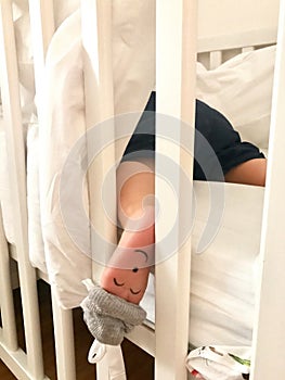 Small little boy sleeping in his cot with a closed eyes face painted on his left foot