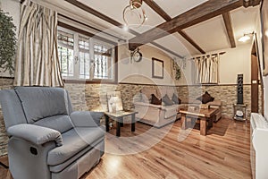 A small living room on the ground floor of a detached house with fabric upholstered sofas, wooden floors, small windows