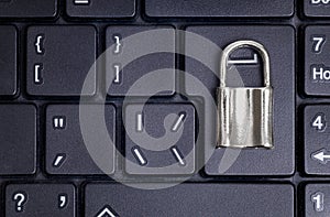 Small locked steel padlock on a black laptop keyboard