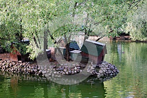 Small lodges for birds on the bank of a pond in Moscow Zoo.