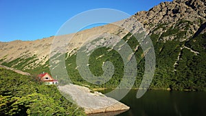 Small lonely house on rock next to mountain lake in warm evening light, Mountain hut Refugio Jakob or San Martin photo