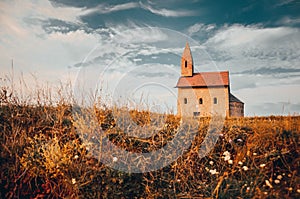 Small man on the bicycle near by old catholic church in slovakia on rocks hill during summer sunset