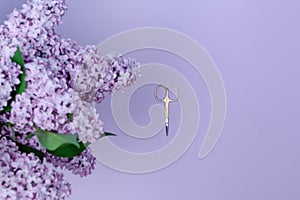 Small manicure scissors and a lilac bouquet on a purple background.