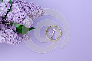 Small manicure scissors and a scotch tape with lilac bouquet on a purple background.