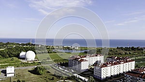 Small mediterranean town located by the sea. Clip. Panoramic aerial view of a beautiful green city and the sea on blue