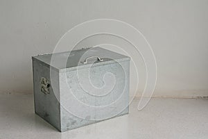 Small metal container on concrete floor in white room.