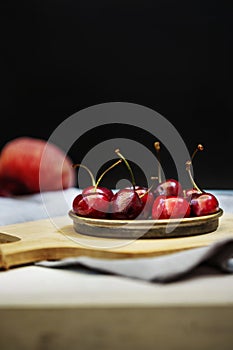 A small metal saucer filled with ripe cherries