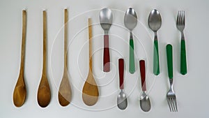 Small metal and wooden spoons, forks, wooden arranged on white background, kitchen utensils