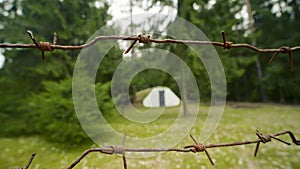 Small military old bunker surrounded by barbed wire in summer forest