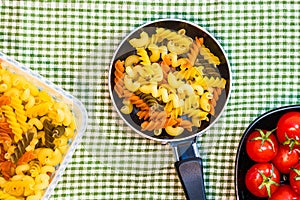 Small mini frying pan with tricolor raw fusilli pasta in a rustic composition