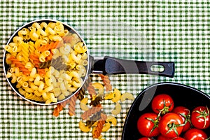 Small mini frying pan with tricolor raw fusilli pasta in a rustic composition