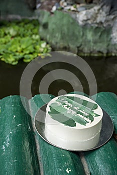 A small minimalist cake on a faux bamboo bridge by a koi pond. With Tagalog words translated as 1 year and forever. photo