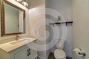 Small minimalist residential home bathroom with toilet sink cabinet and mirror