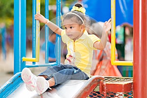 Small mixed race girl using a slide at a playground