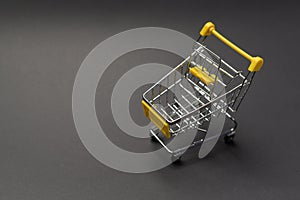 Small model shopping cart over black background studio