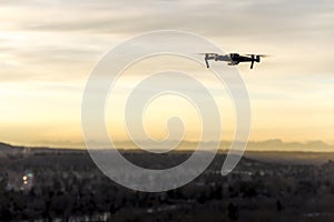 Small modern drone hovering taking picture of sunset