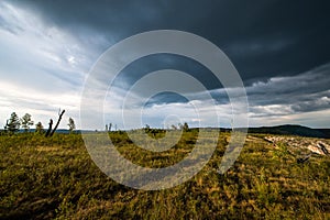 Small mountains, illuminated by the setting sun, and storm clouds in the sky