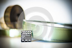 Small movie clapper board with film in background