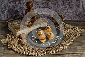 Small muffins topped with chopped almonds on a gray plate, with a wicker placemat and a wooden nutcracker