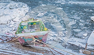 Small multicolor fishing boats trapped on frozen river Danube