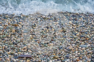 Small multicolored sea pebbles washed by a wave.